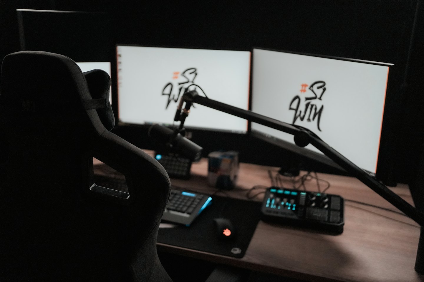 Gaming setup with multiple monitors, microphone, and audio mixer.